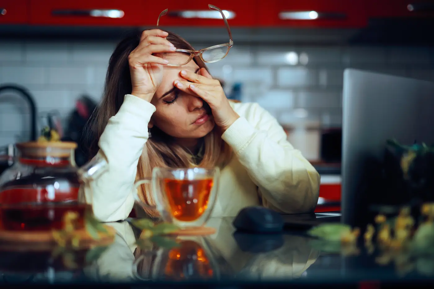 Woman at her desk struggling to work through a migraine.